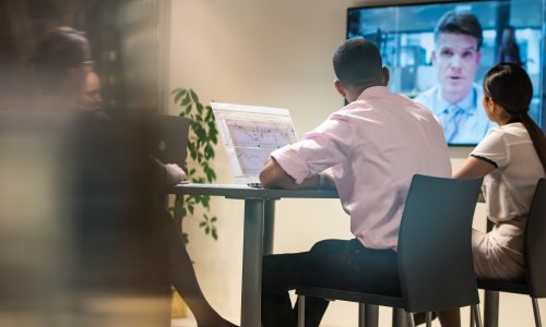 Business people sitting in board room during video conference meeting.